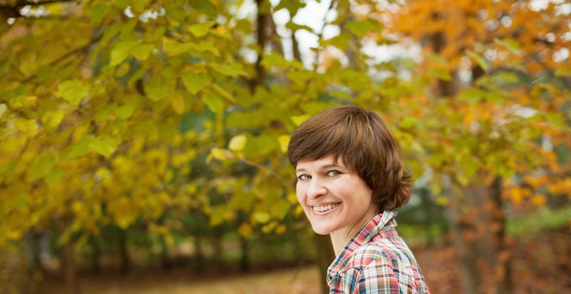 Woman smiling underneath trees.